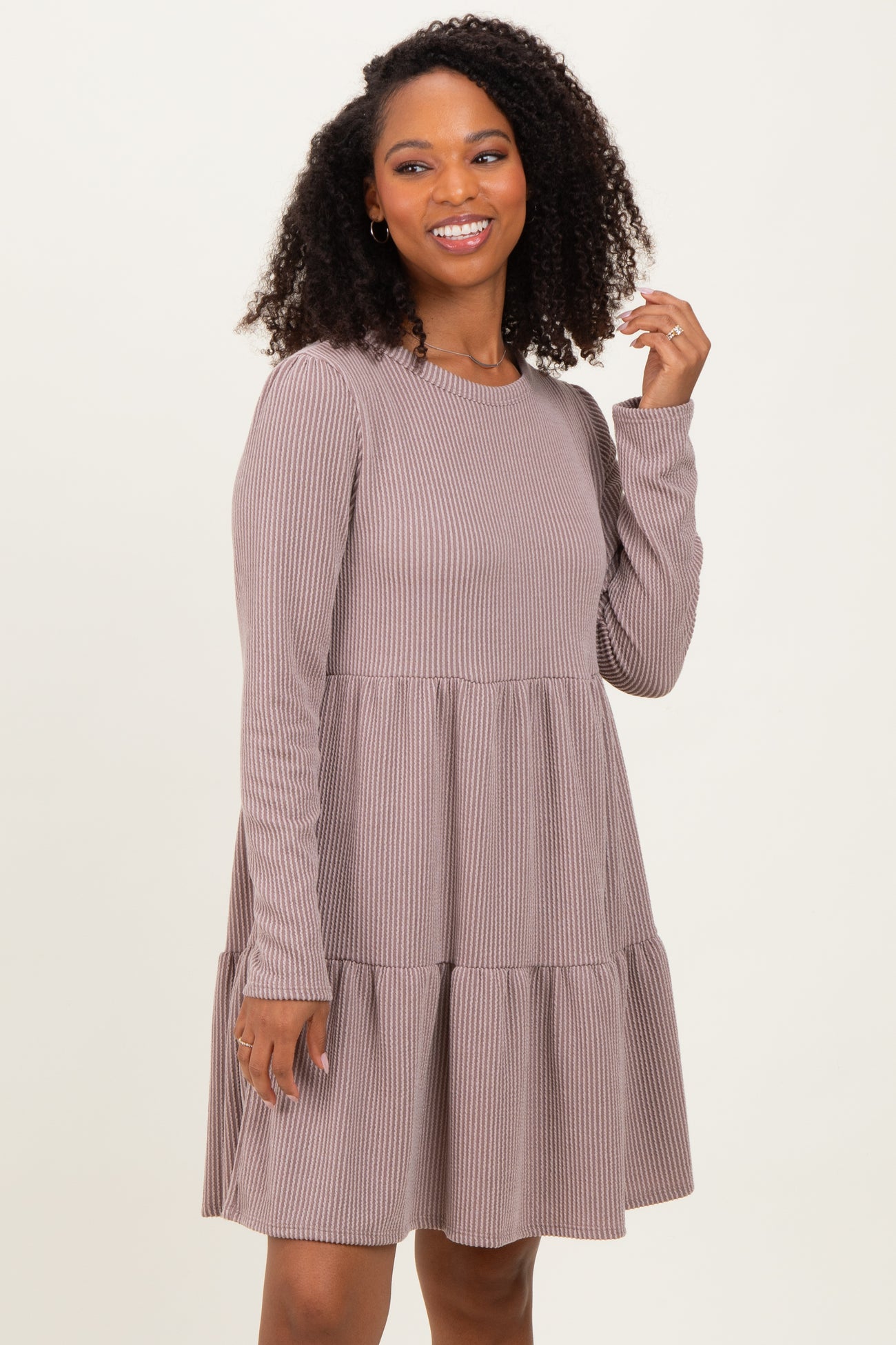 woman wearing a taupe ribbed long sleeve dress with a flared tiered skirt and a round neckline