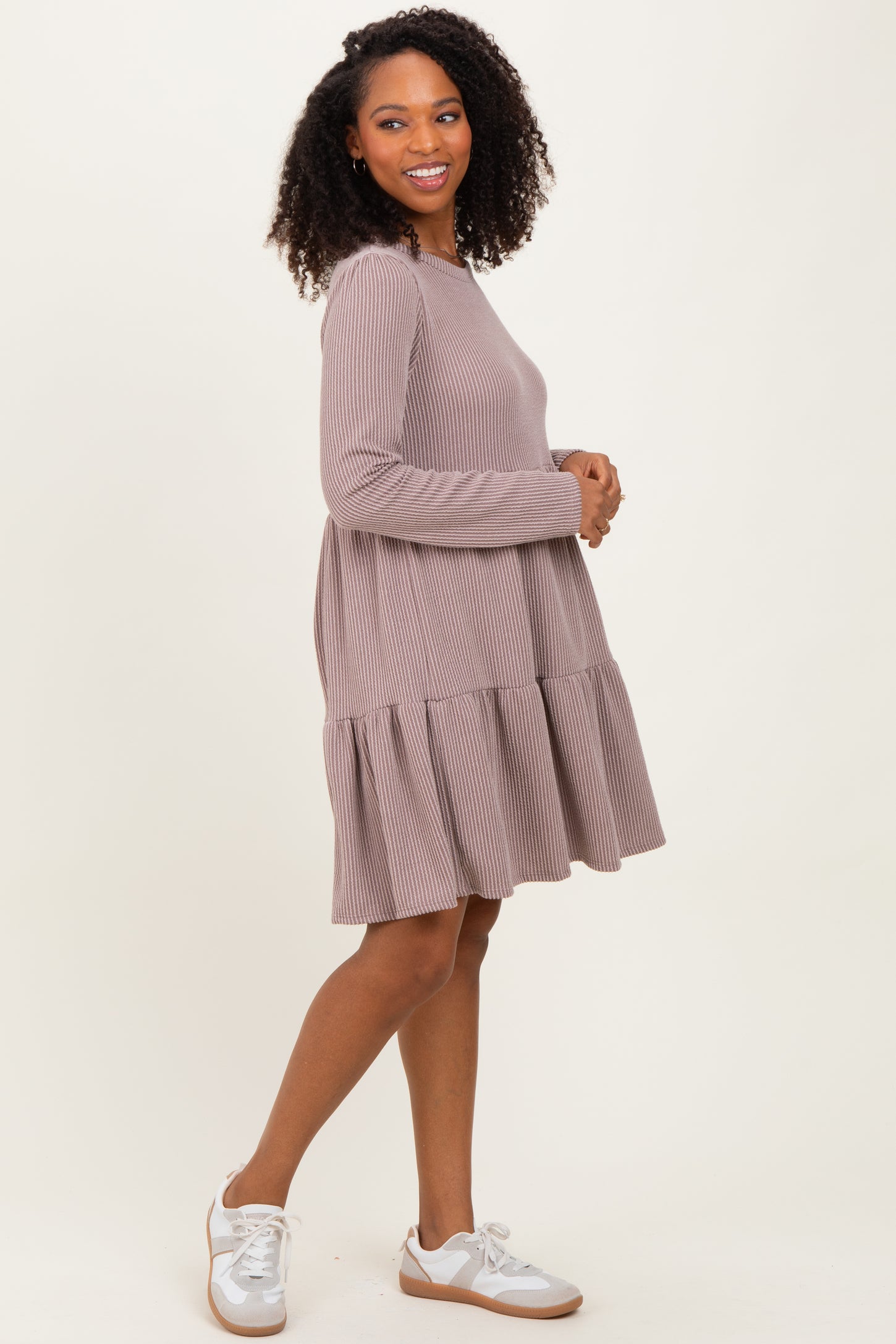 woman wearing a taupe ribbed long sleeve dress with a tiered skirt and white sneakers