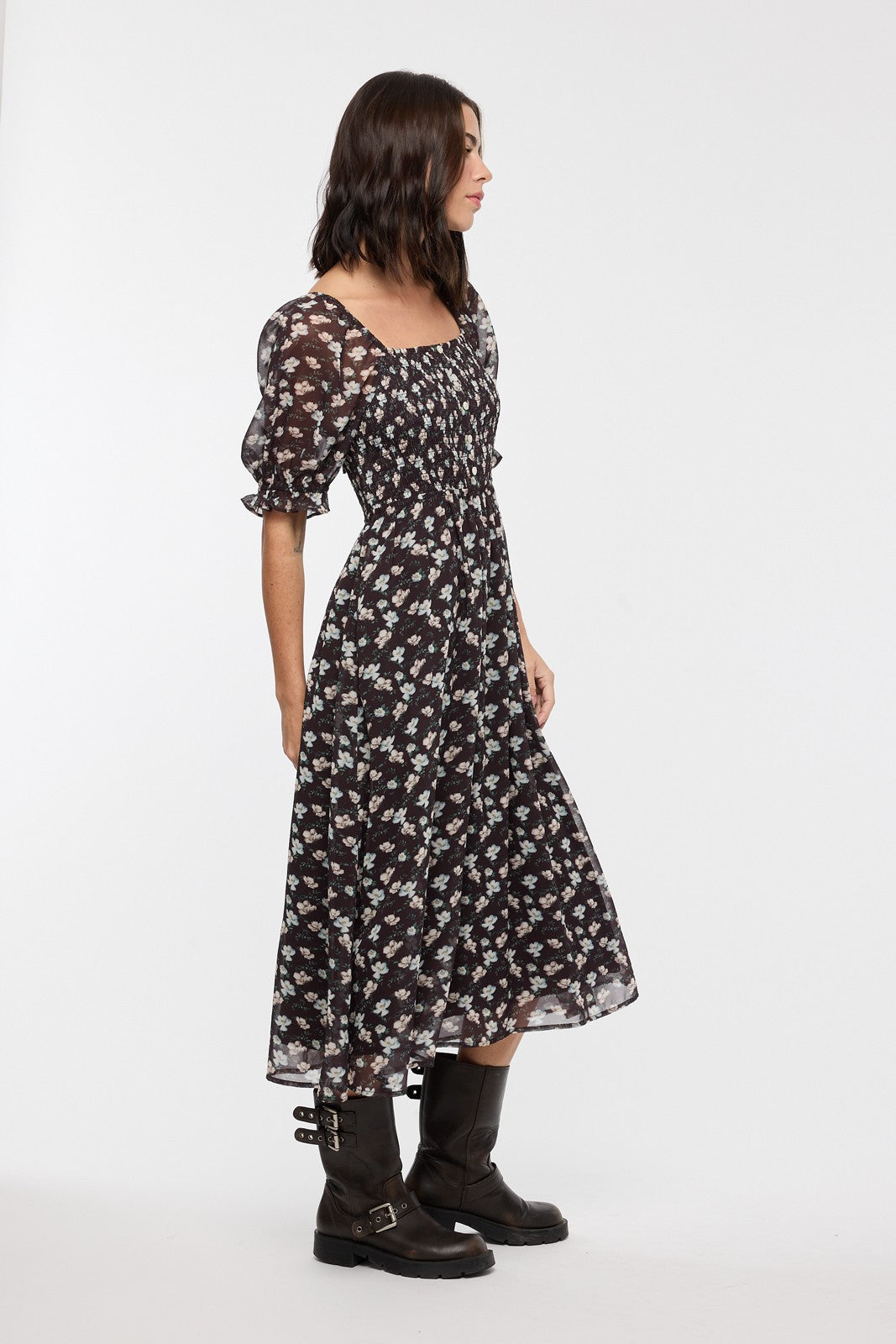woman wearing a black floral midi dress with puff sleeves and a fitted bodice, posing in profile