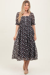 woman wearing a black floral midi dress with short puff sleeves and a smocked bodice
