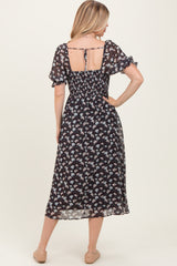woman wearing a black floral midi dress with puff sleeves and an open back detail