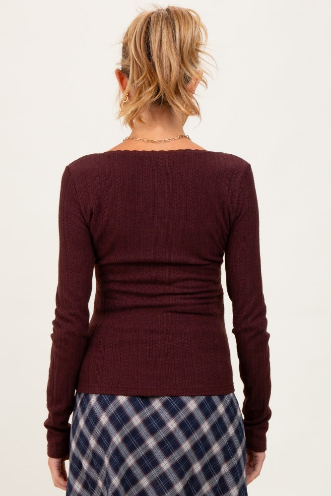 woman wearing a maroon maternity long sleeve top with a fitted style, viewed from the back