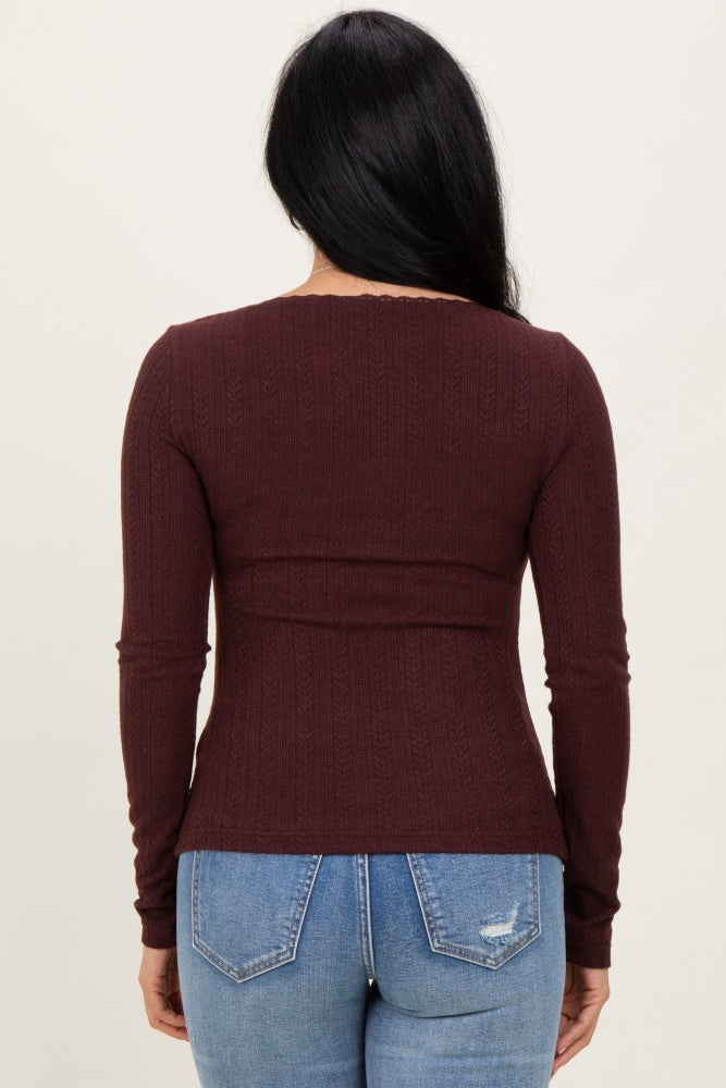 woman wearing a burgundy long sleeve ribbed top with a fitted silhouette, viewed from the back
