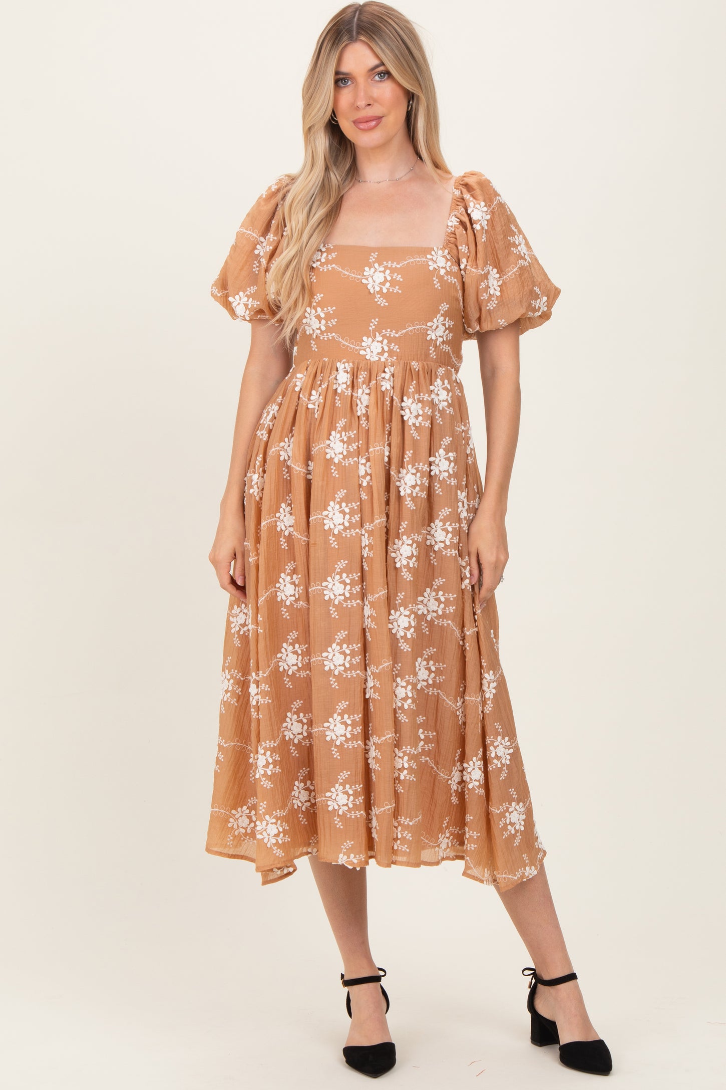 woman wearing a brown floral midi dress with puff sleeves and a square neckline, styled with black heels