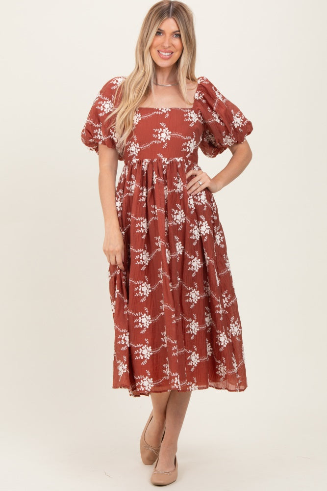 woman wearing a rust-colored floral print midi dress with puff sleeves and a square neckline