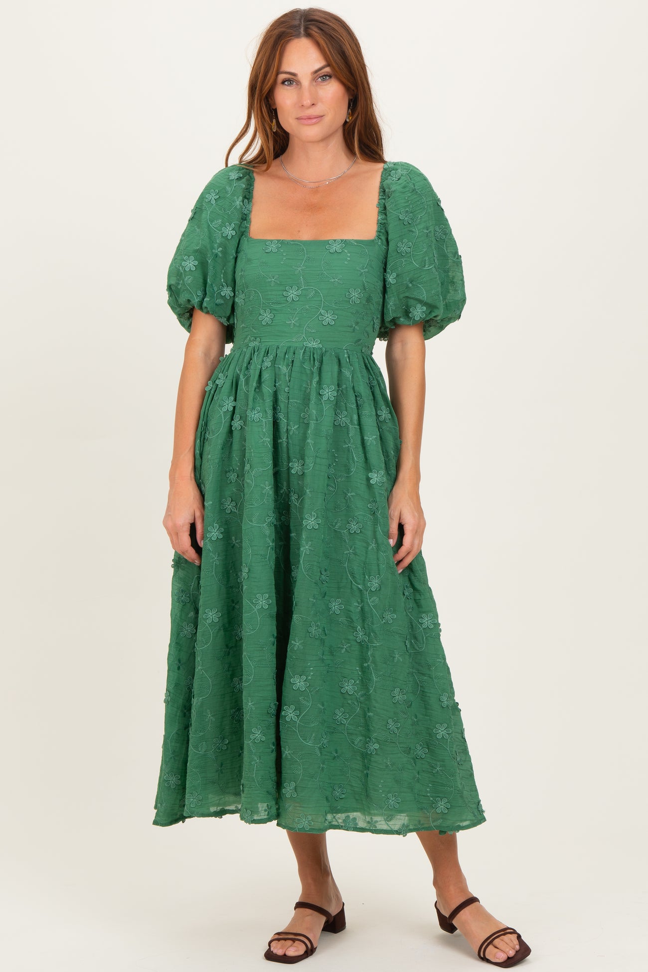 woman wearing a green puff sleeve midi dress with a square neckline and floral embroidery