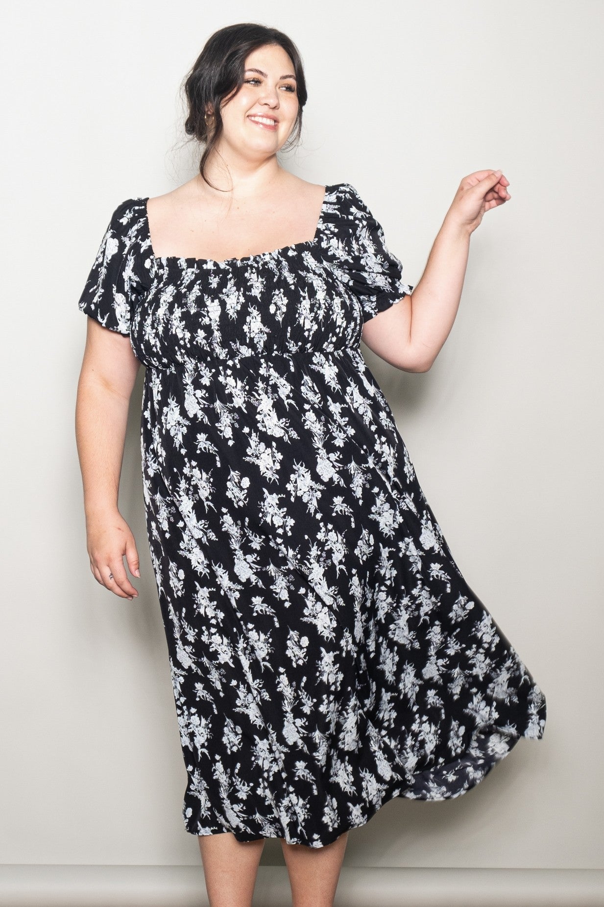 woman wearing a black floral print plus size dress with short sleeves and a square neckline