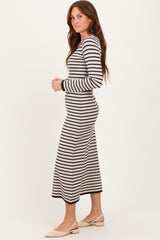 woman wearing a long sleeve striped maxi dress in black and cream, standing sideways with a relaxed fit