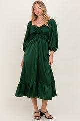 woman wearing a dark green puff sleeve midi dress with a gathered front and ruffle hem, standing in a relaxed pose