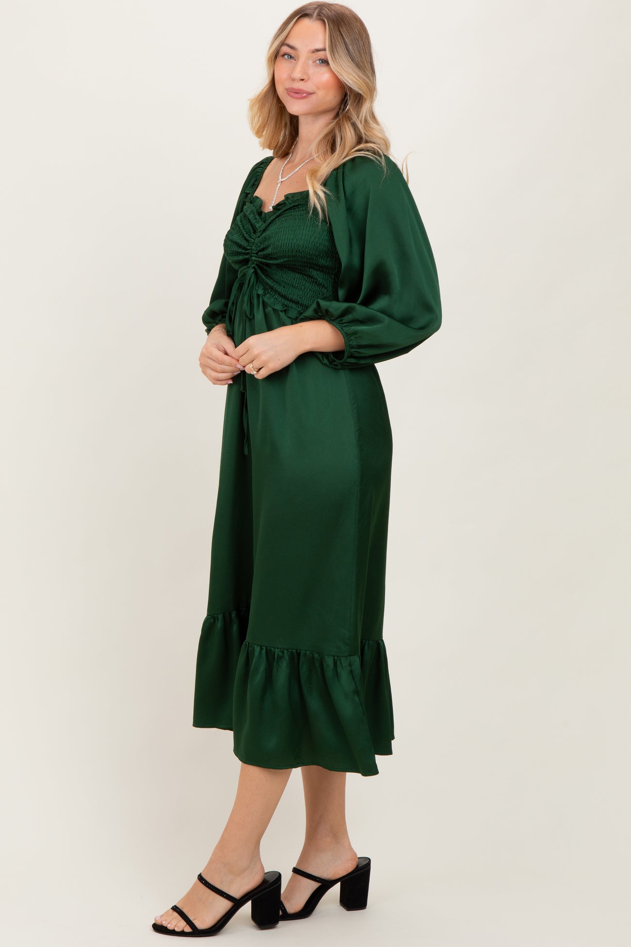 woman wearing a green smocked midi dress with puff sleeves and a ruffled hem, styled with black strappy heels