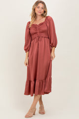 woman wearing a rust-colored midi dress with smocked bodice and puff sleeves, styled with a tiered ruffle hem