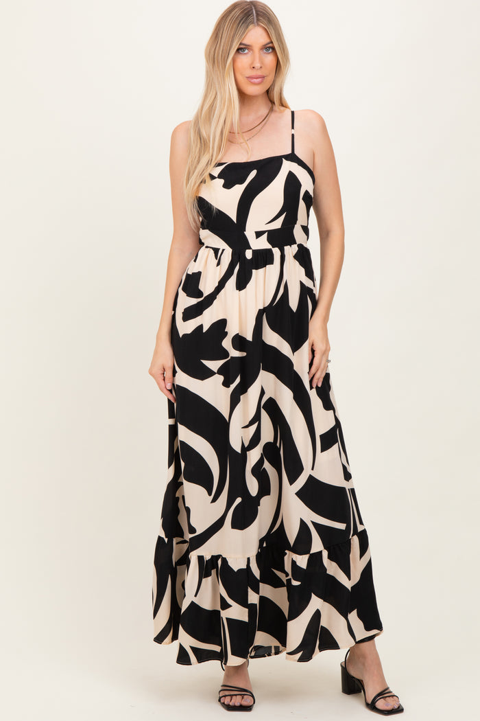 woman wearing a black and cream maxi dress with abstract print and tiered hem, standing and smiling