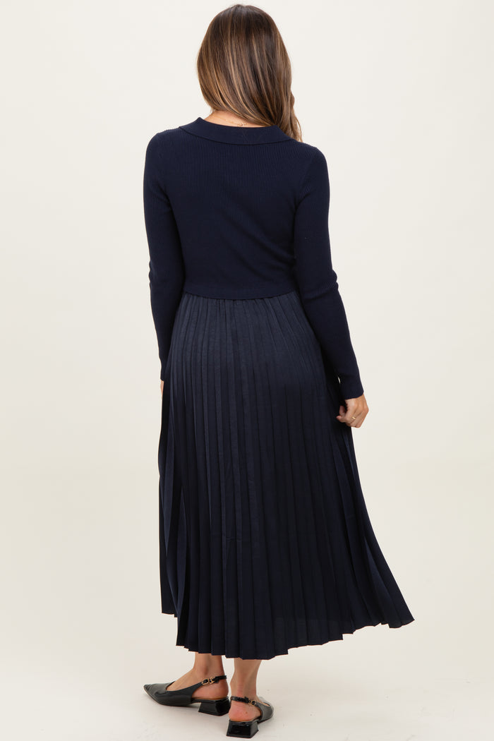 woman wearing a navy blue long sleeve maternity dress with a pleated skirt, showing her back and no visible baby bump
