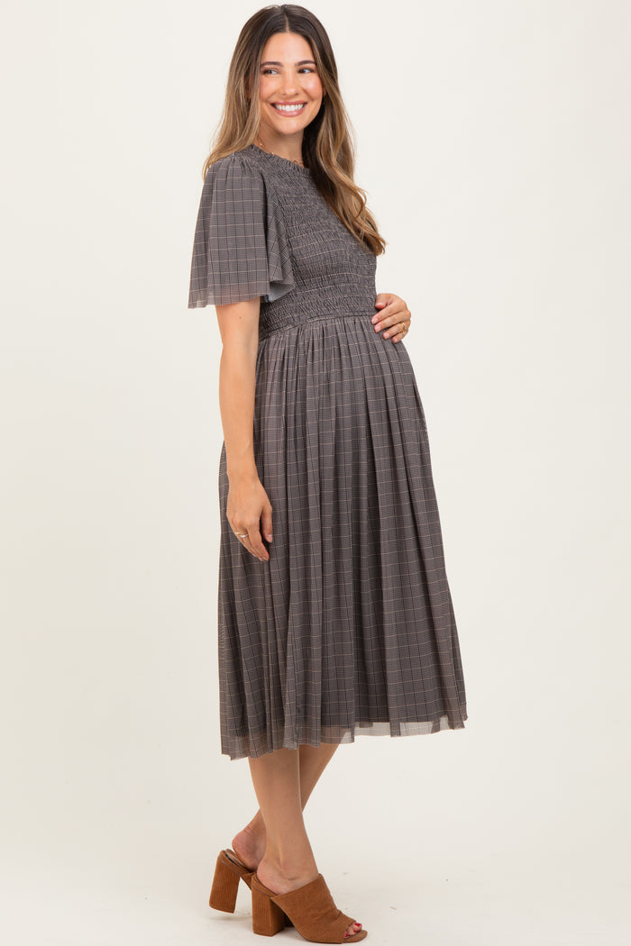 woman wearing a gray maternity dress with short flutter sleeves and a smocked bodice, showing her baby bump