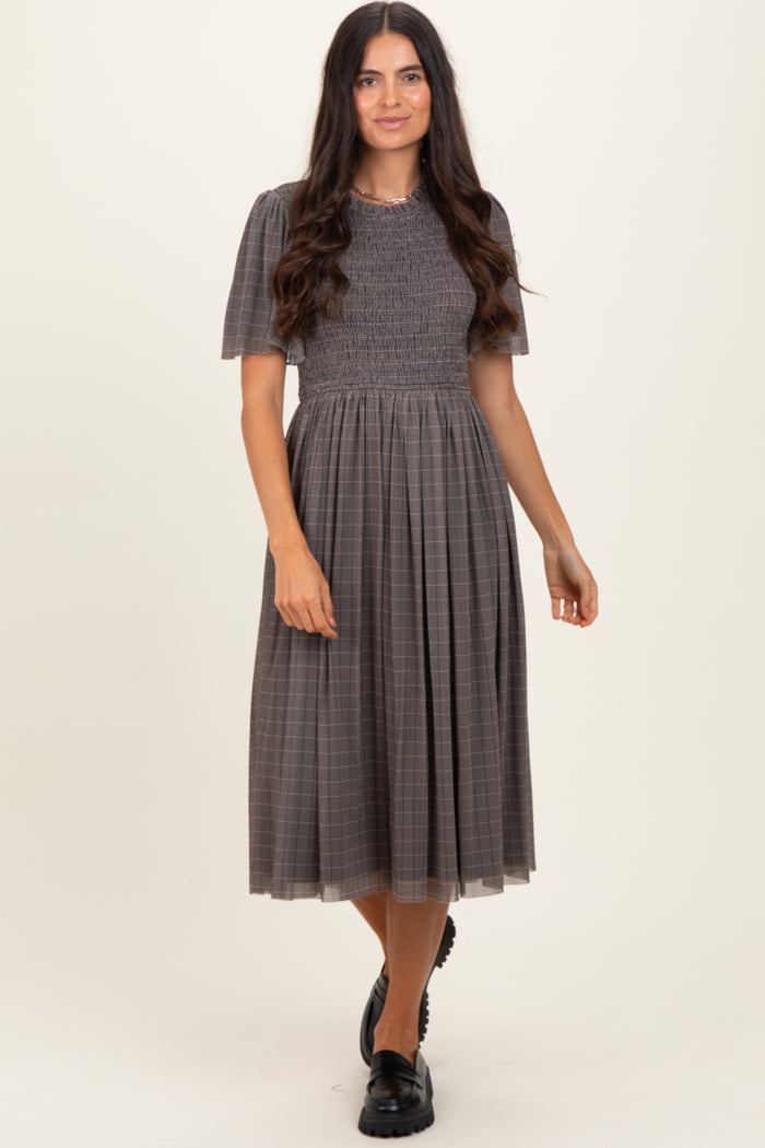 woman wearing a grey checkered midi dress with short puff sleeves and a smocked bodice