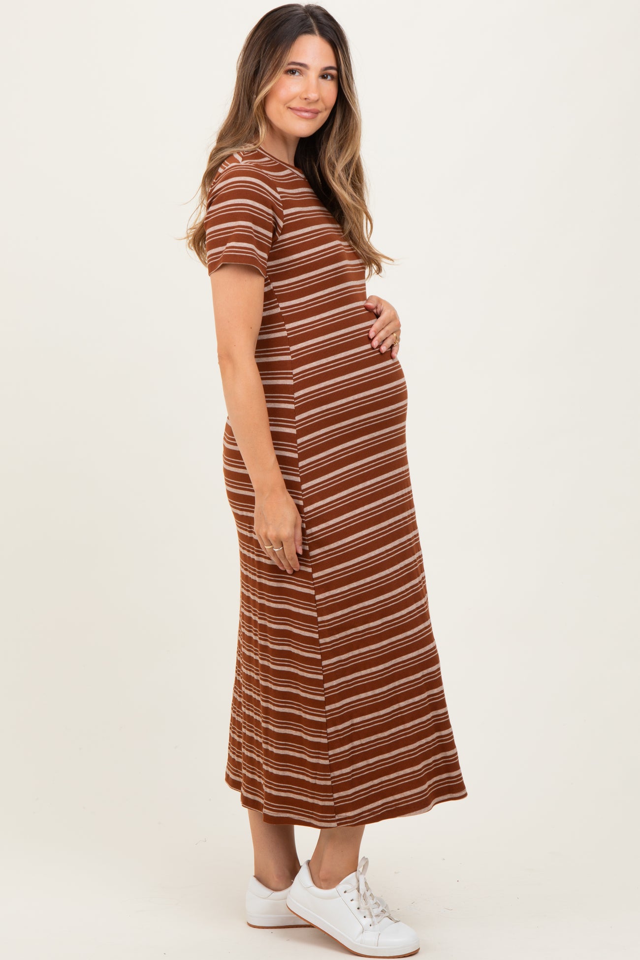 woman wearing a brown striped maternity dress and holding her baby bump