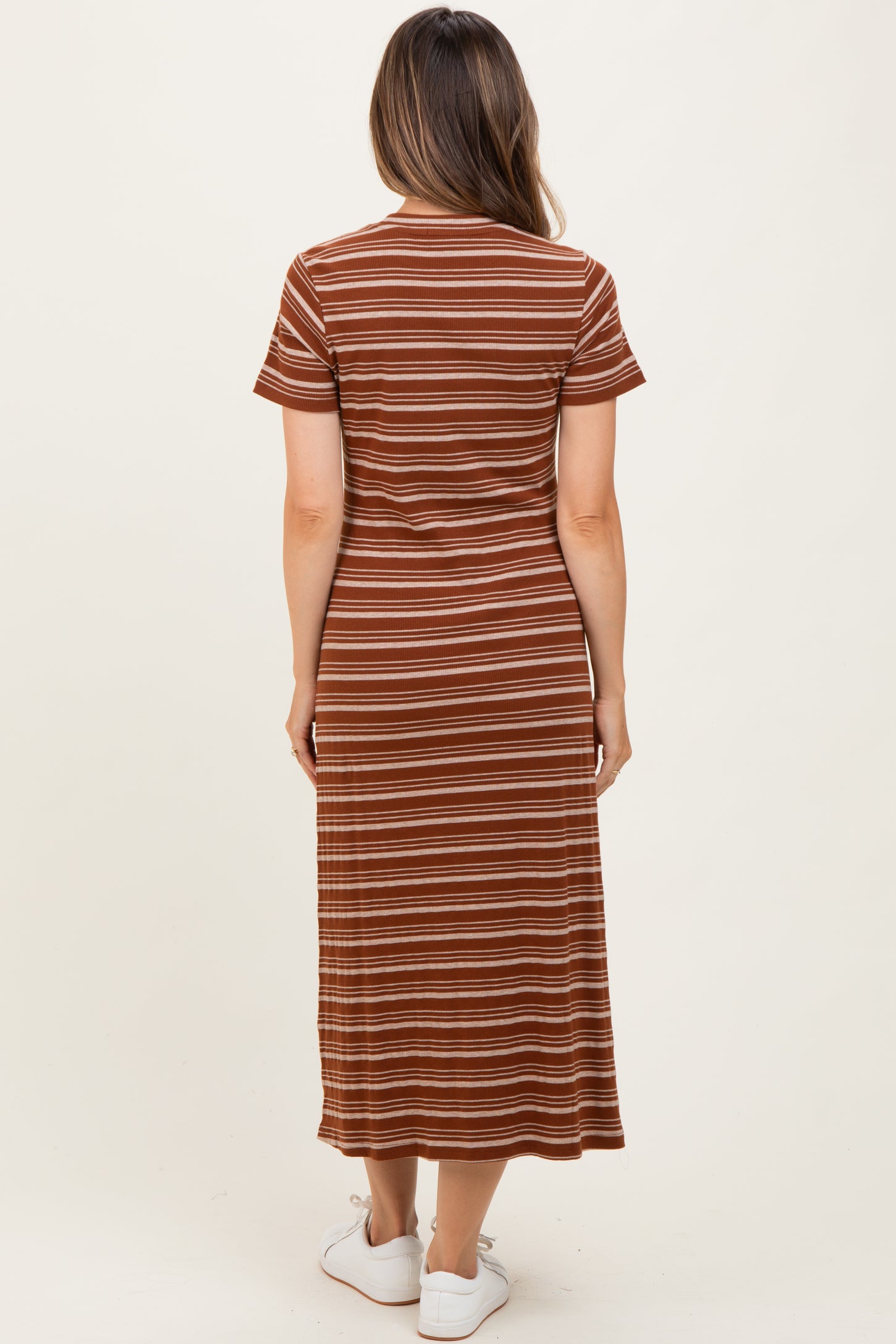 woman wearing a rust and cream striped maternity maxi dress standing with her back to the camera