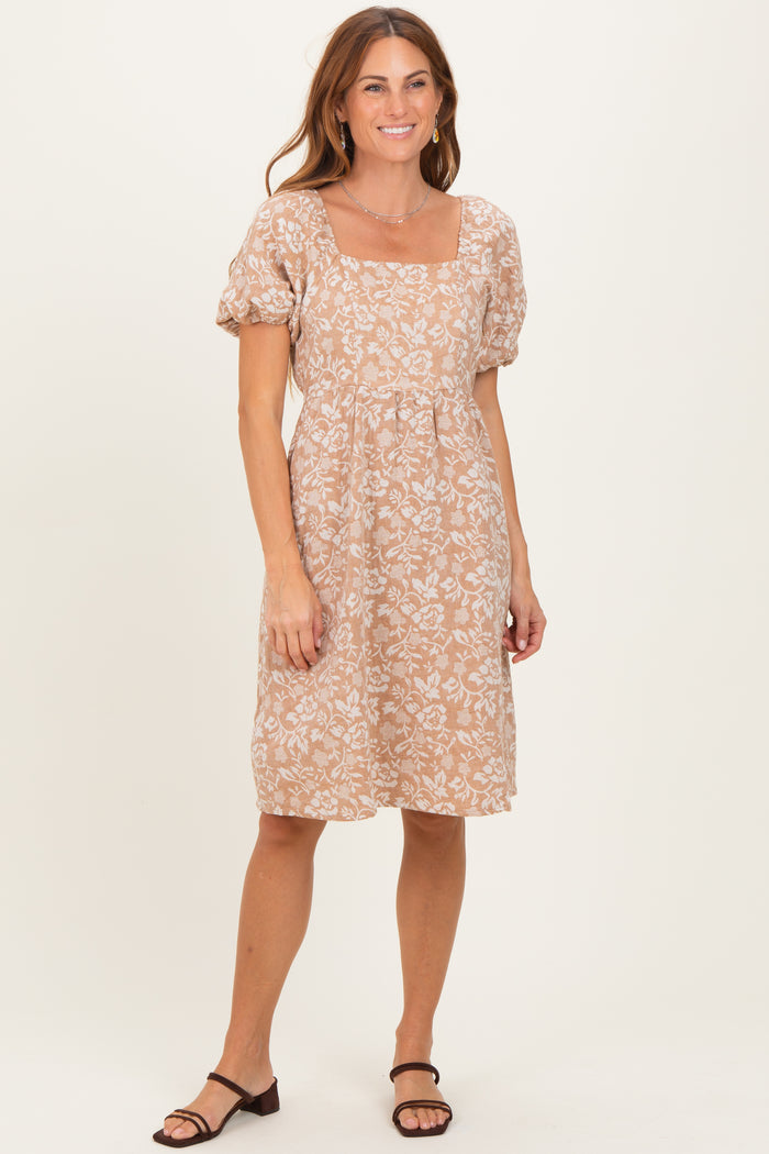 woman wearing a short beige floral print dress with puffed sleeves and a square neckline