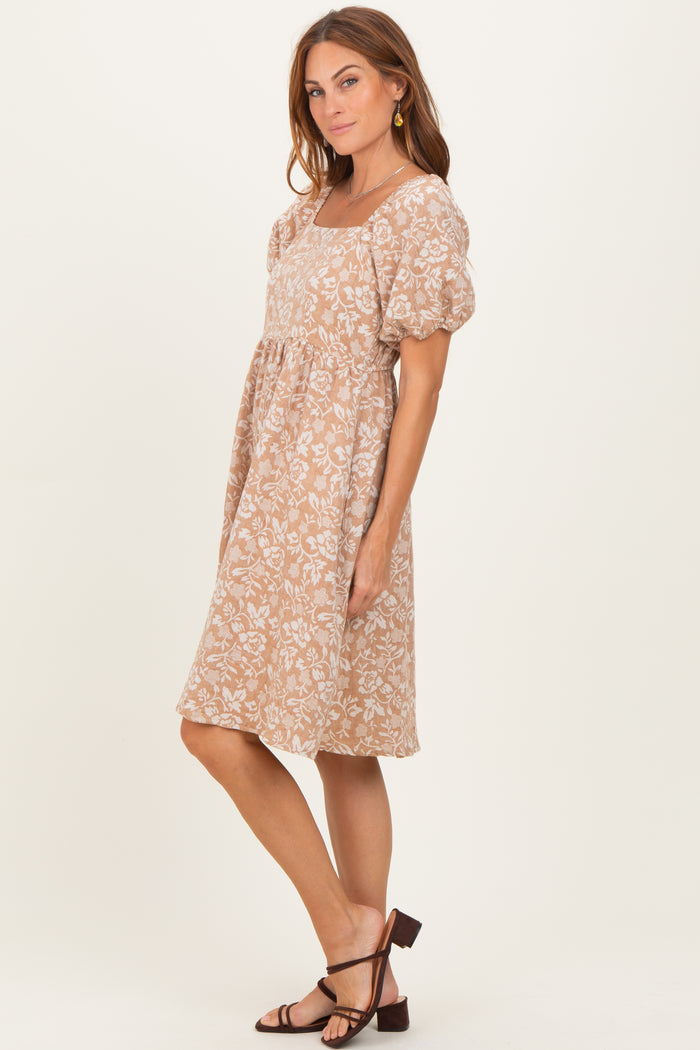 woman wearing a tan floral print puff sleeve dress and strappy brown sandals