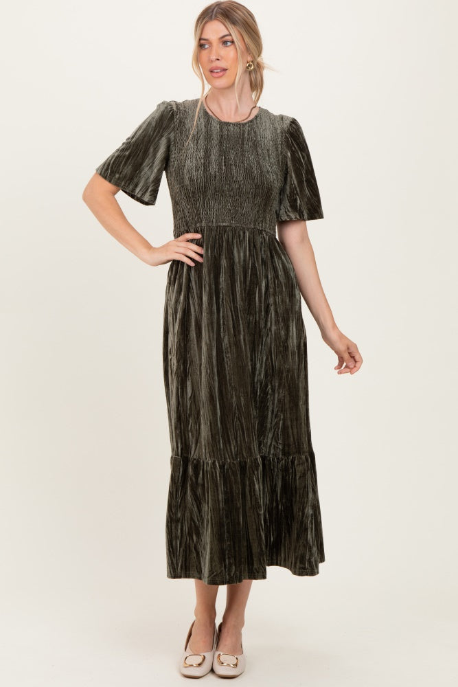 woman wearing a dark green velvet maxi dress with short sleeves and a tiered skirt