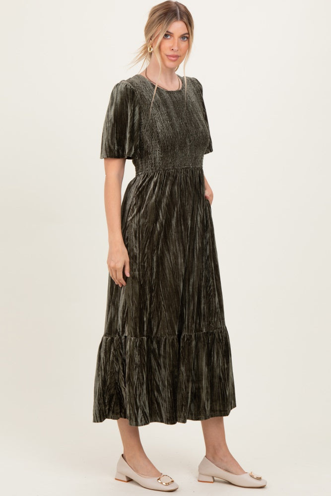 woman wearing an olive green crushed velvet midi dress with short sleeves and ruffle hem details