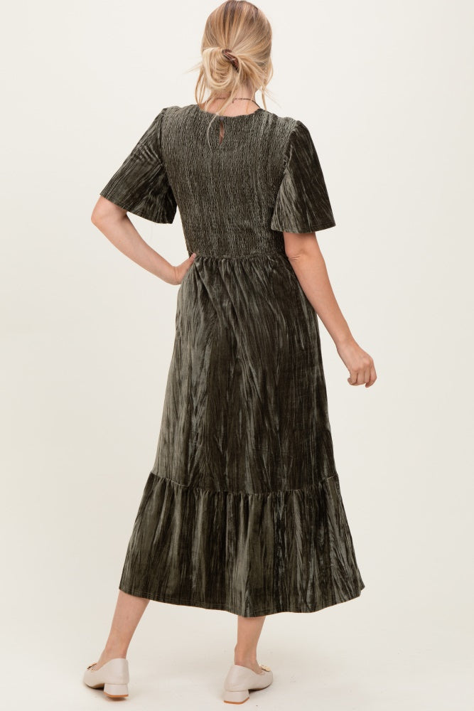 woman wearing an olive green velvet maxi dress with short sleeves and a tiered skirt, viewed from the back