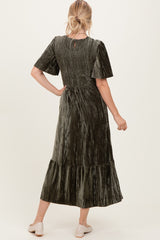 woman wearing an olive green velvet maxi dress with short sleeves and a tiered skirt, viewed from the back
