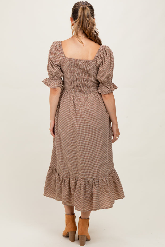 woman wearing a brown checkered maternity dress with a smocked bodice and ruffled hem, showing her back