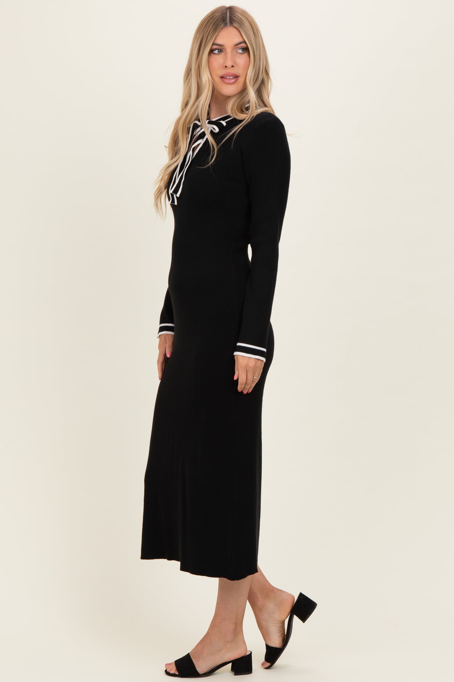 woman wearing a black ribbed midi dress with long sleeves and white stripe detailing on the cuffs and collar