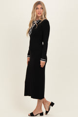 woman wearing a black ribbed midi dress with long sleeves and white stripe detailing on the cuffs and collar