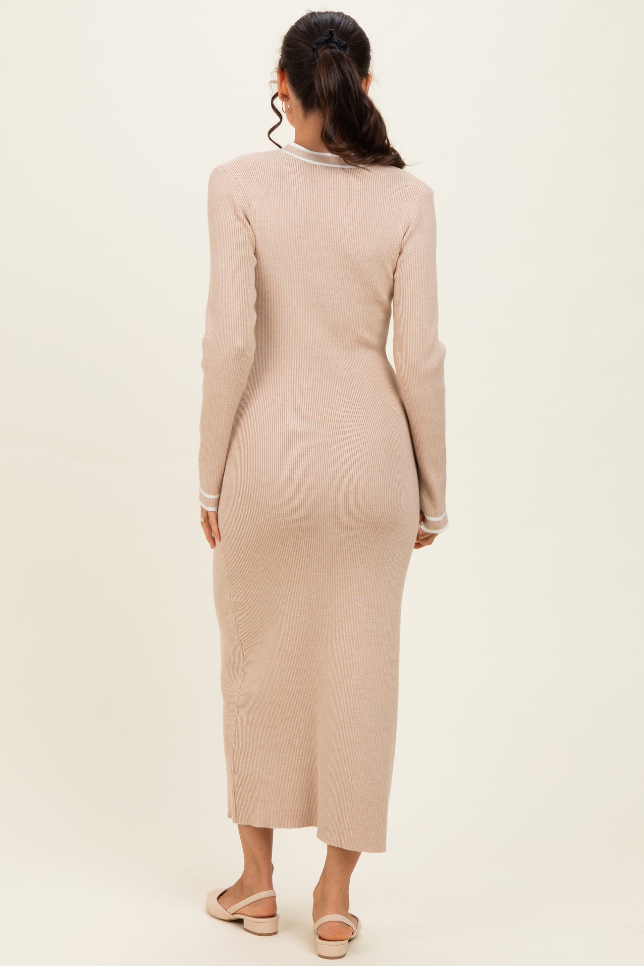 woman wearing a beige ribbed midi dress with long sleeves and a side slit, viewed from the back
