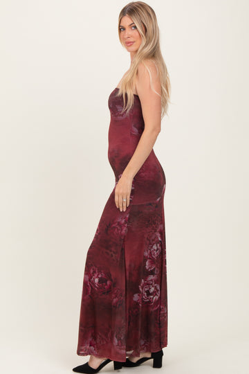 woman wearing a burgundy floral maxi dress with a fitted silhouette and side slit, posing sideways with long hair down