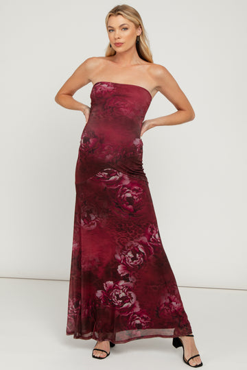 woman wearing a burgundy strapless maternity maxi dress with floral design and a visible baby bump