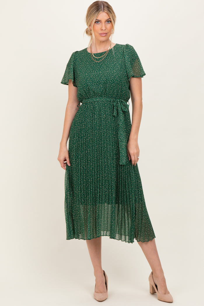 woman wearing a green floral midi dress with short sleeves and a tie waist, styled with nude heels and layered necklaces