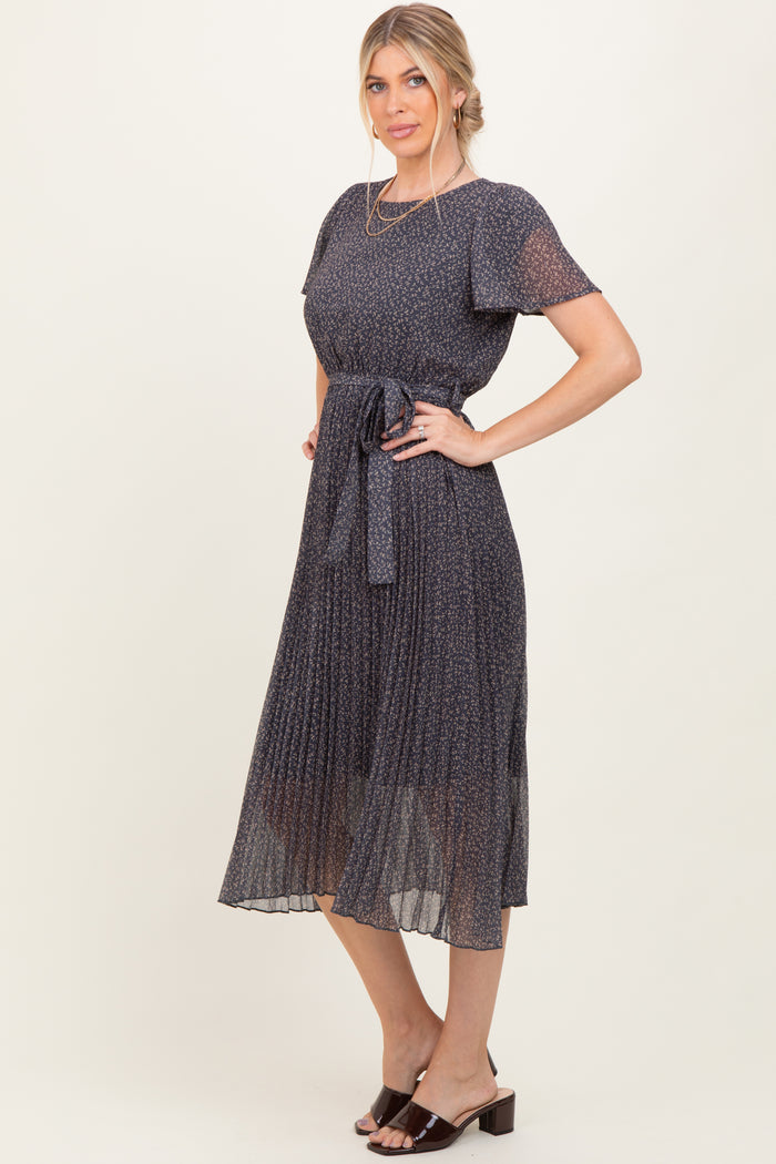 woman wearing a navy blue pleated midi dress with short sleeves and a tied waist detail