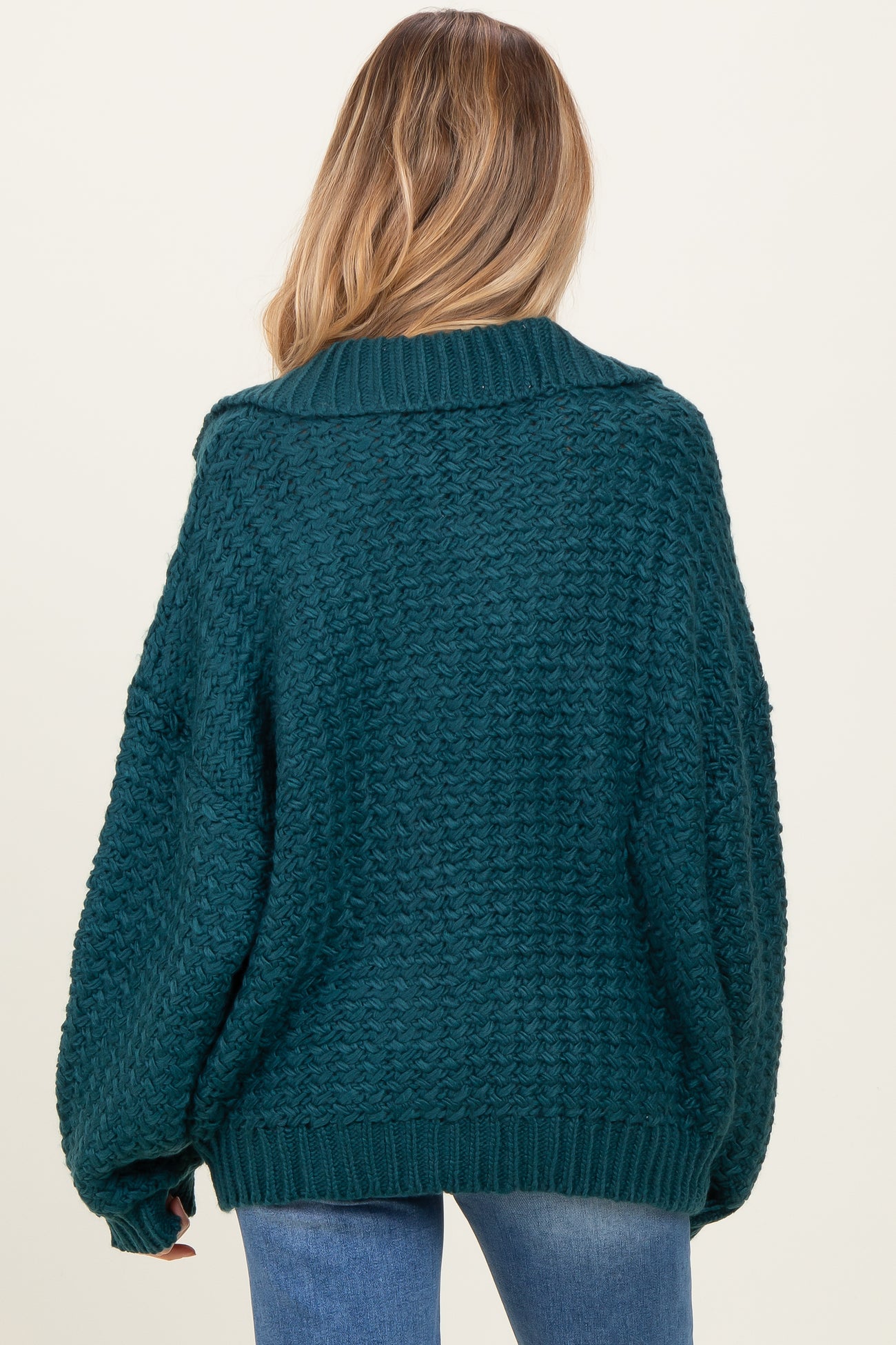 woman wearing a teal oversized knitted maternity sweater with a cozy design and dropped shoulders