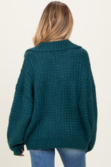 woman wearing a teal oversized knitted maternity sweater with a cozy design and dropped shoulders
