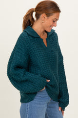 woman wearing a teal oversized knitted sweater with a collar and relaxed fit, paired with blue jeans