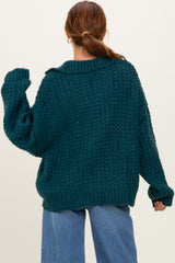 woman wearing a dark teal oversized knitted sweater with a collar and dropped shoulders, styled with light blue jeans