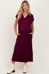woman wearing a burgundy maternity dress with a collar and pockets, featuring white trim detail