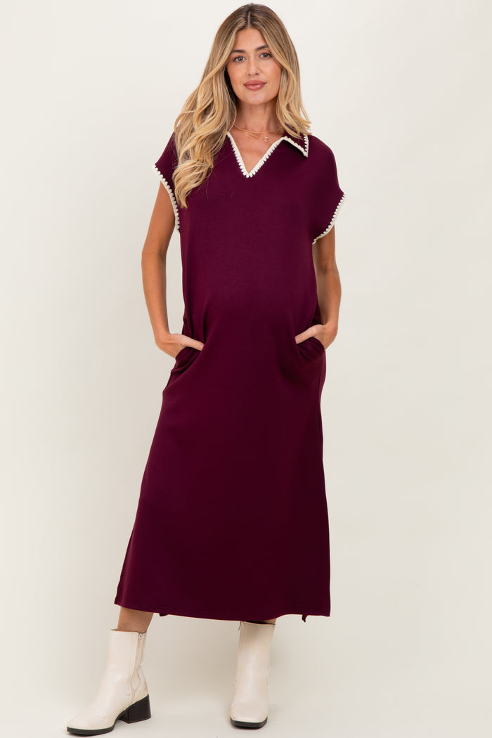 woman wearing a burgundy maternity dress with a collar and pockets, featuring white trim detail