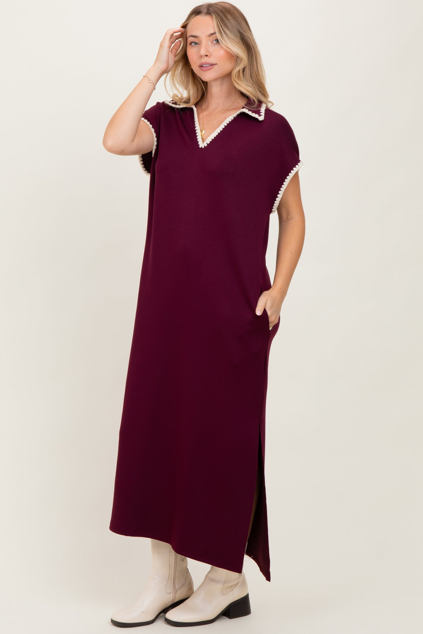 woman wearing a burgundy maxi dress with a polo collar and side pockets, featuring a split at the hem