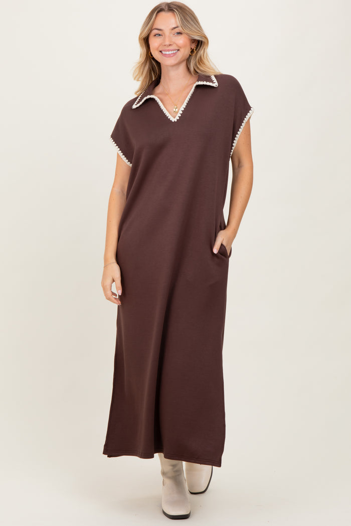 woman wearing a brown maxi dress with a collar and pocket details, standing against a neutral background