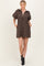 woman wearing a brown leopard print short dress with a zip-up collar and puff sleeves, standing with hands in pockets