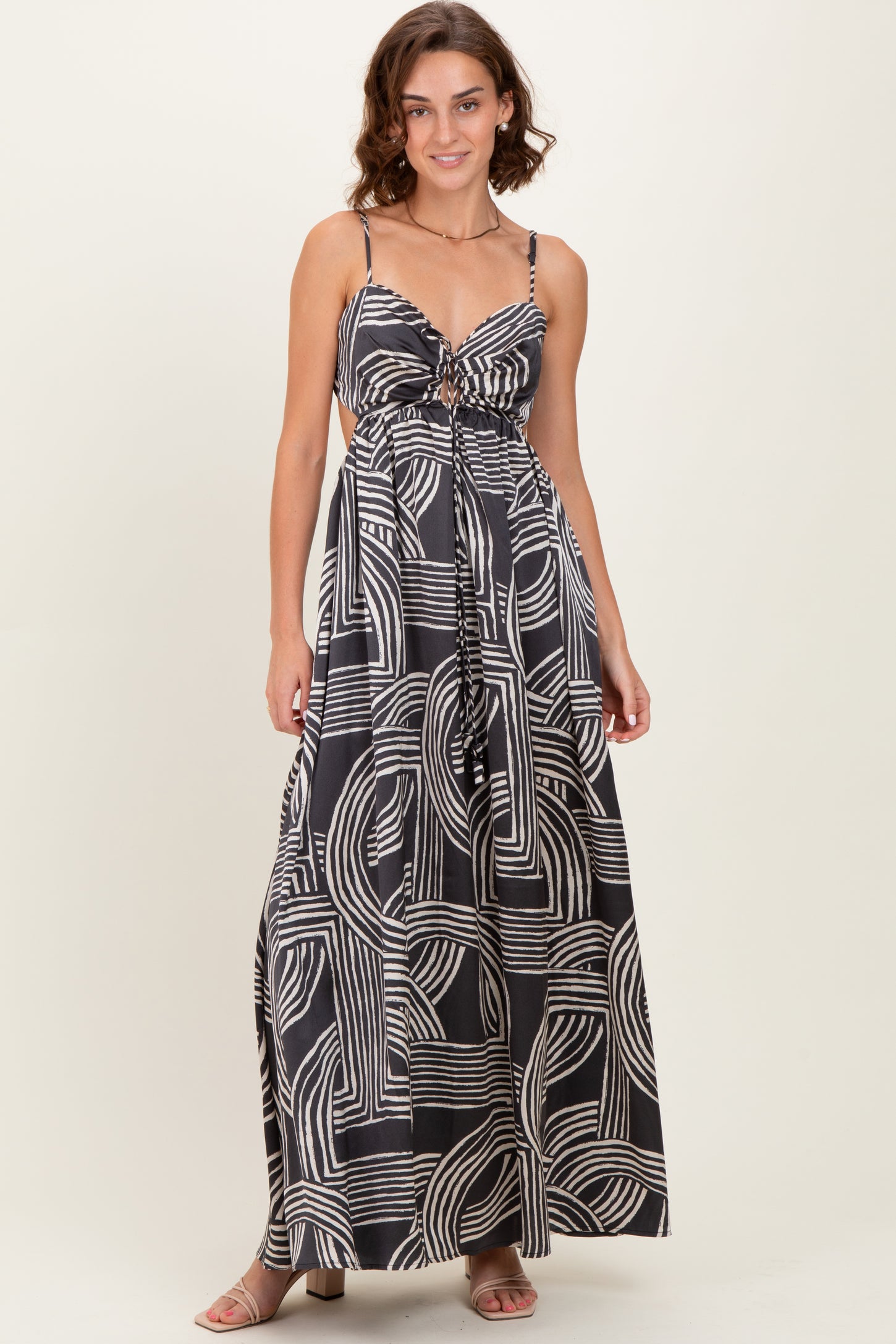 woman wearing a black and white patterned maxi dress with adjustable straps and a tie front detail