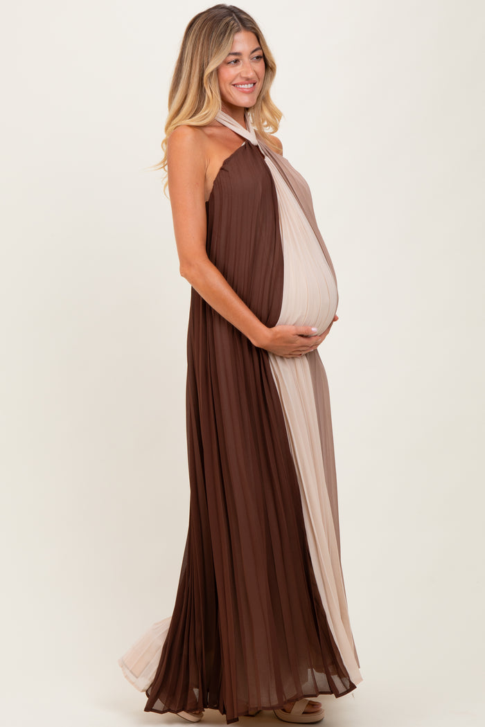 woman wearing a brown and beige pleated maternity dress, holding her baby bump