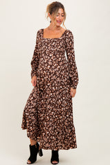 woman wearing a brown floral maternity maxi dress with long sleeves and a square neckline, showcasing her baby bump