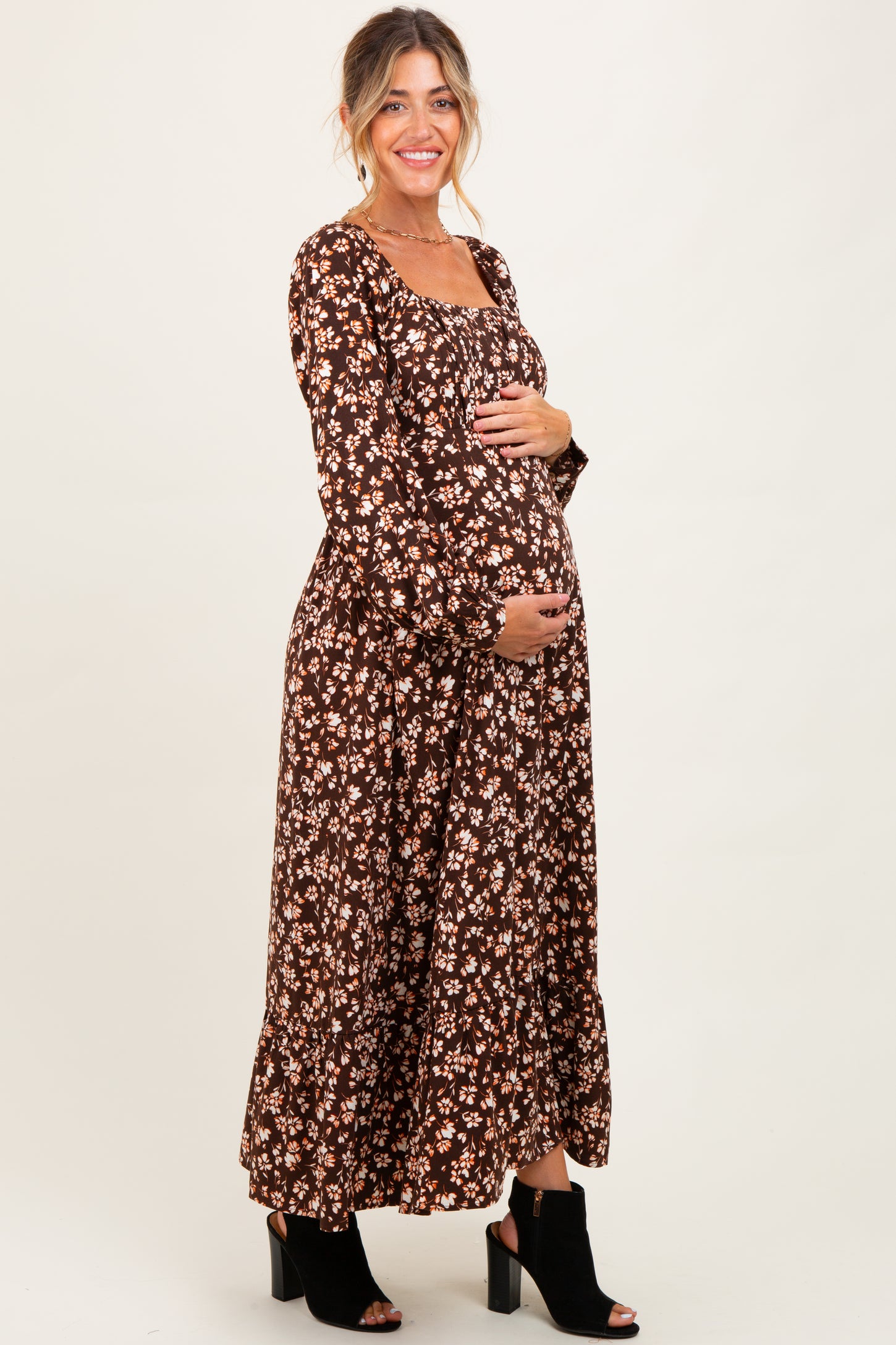 woman wearing a brown floral maternity dress and holding her baby bump