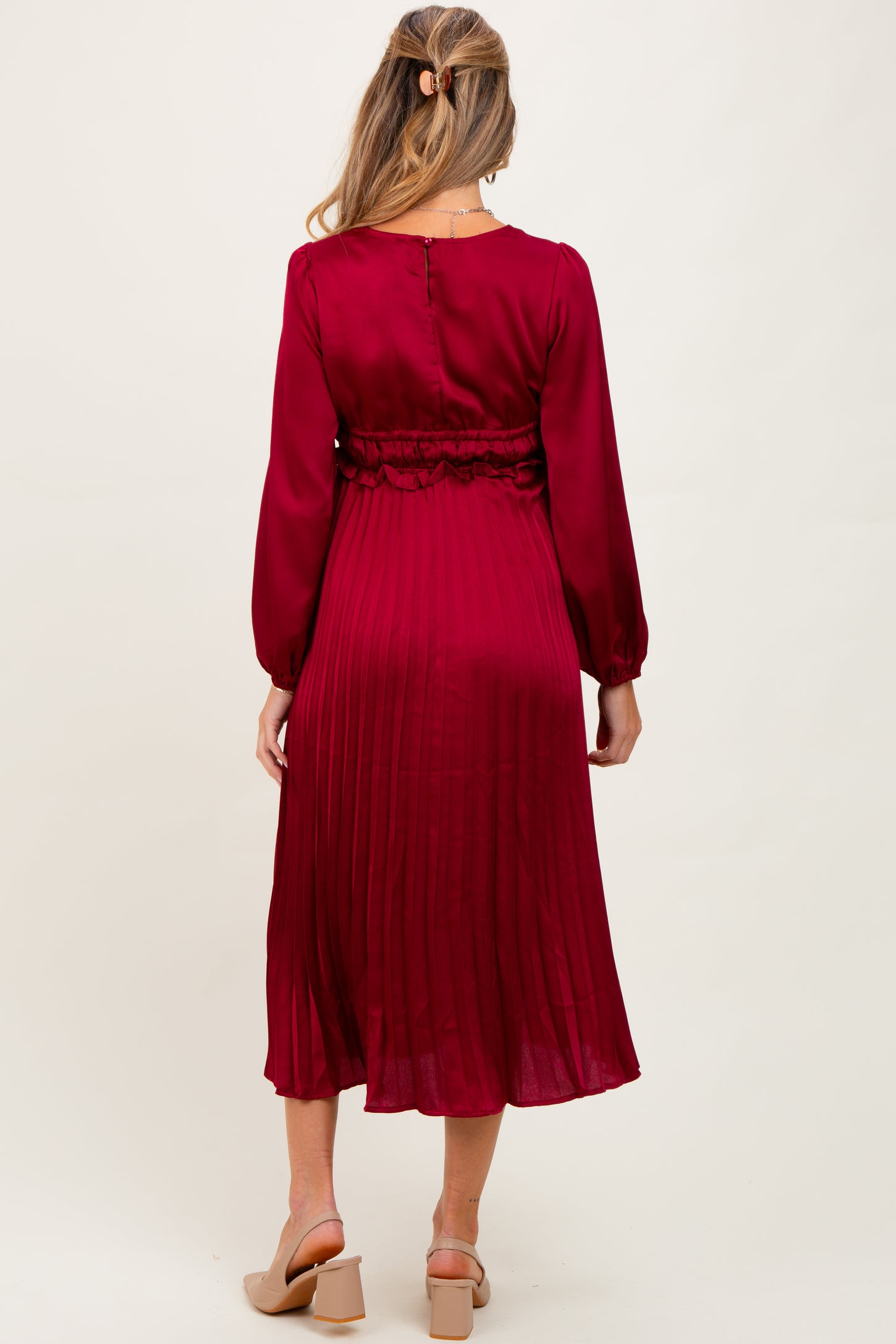 woman wearing a burgundy maternity dress with long sleeves and pleated skirt, showing the back view