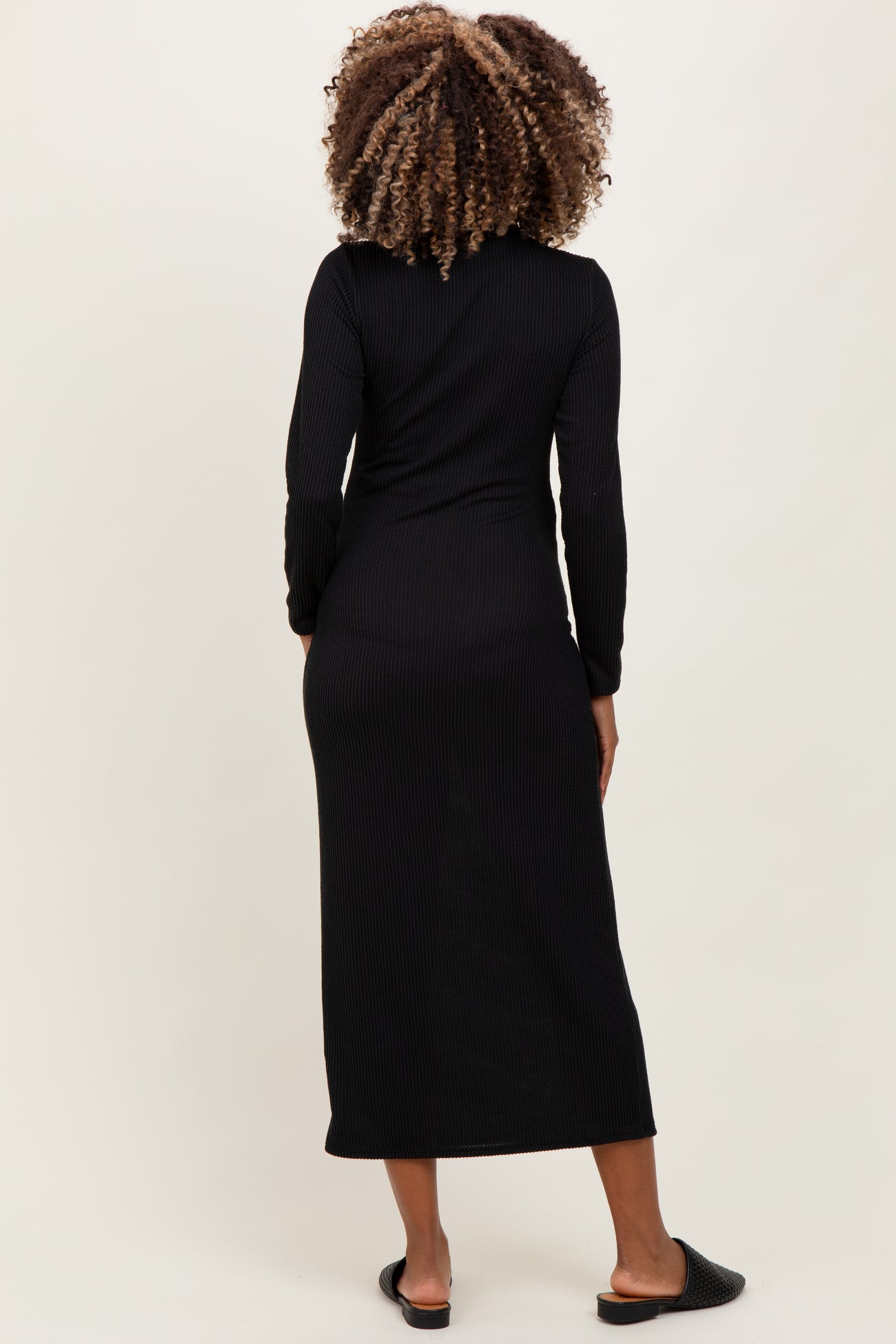 woman wearing a black long sleeve ribbed maternity dress, showing a fitted style from the back